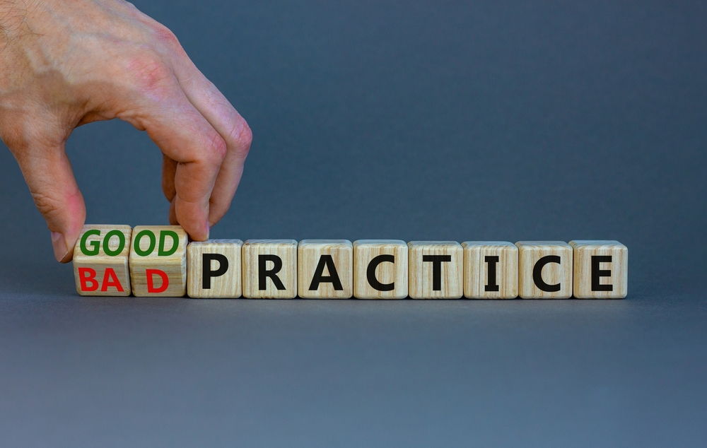 Businessman turns wooden cubes and changes words 'bad practice' to 'good practice'.